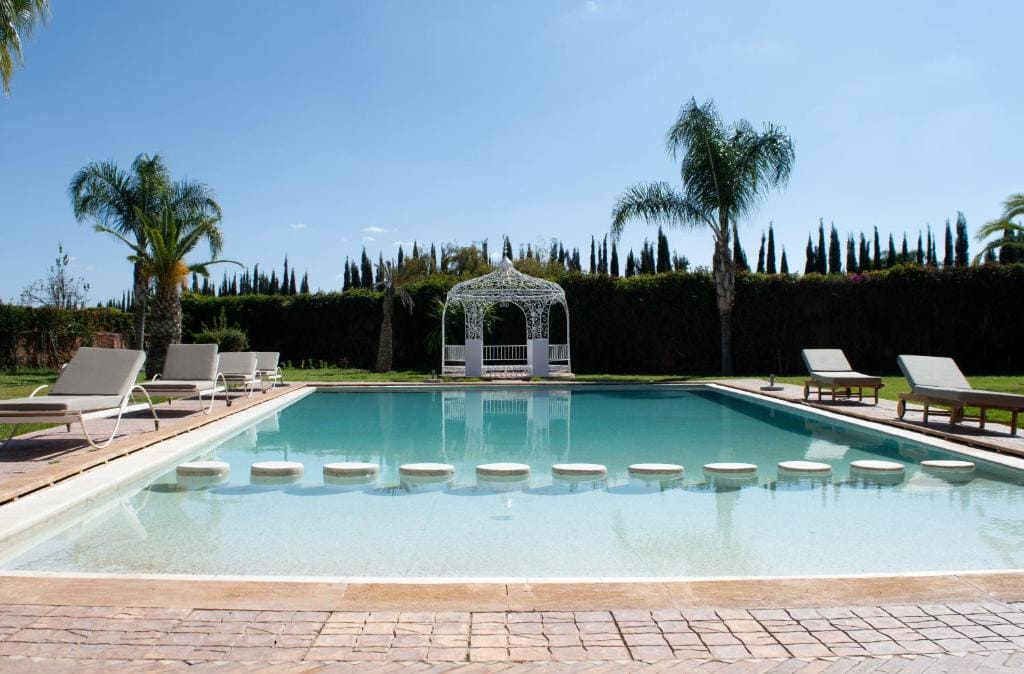 Luxury villa pool area surrounded by palm trees in Marrakech