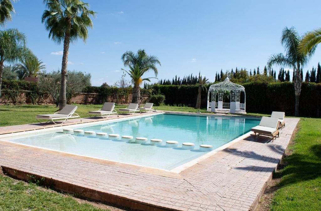 Luxury villa pool area surrounded by palm trees in Marrakech